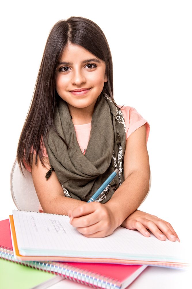 Smiling girl with a scarf writing in a notebook at a desk