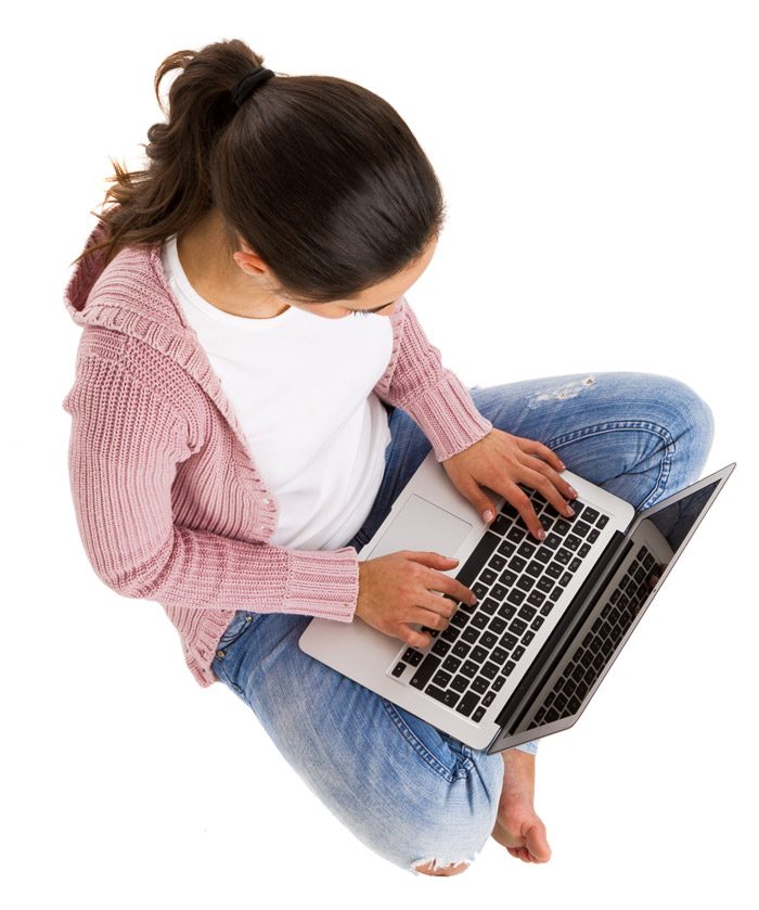 Overhead view of a girl sitting cross-legged and typing on a laptop