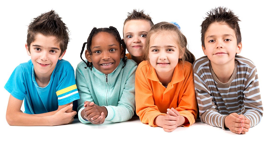 Five smiling children lying on their stomachs side by side