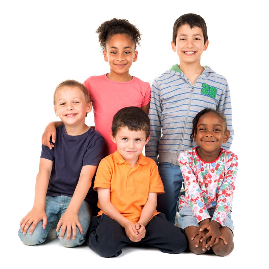A group of five smiling children of different ages sitting and kneeling together