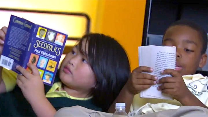 Two young students reading books in a classroom
